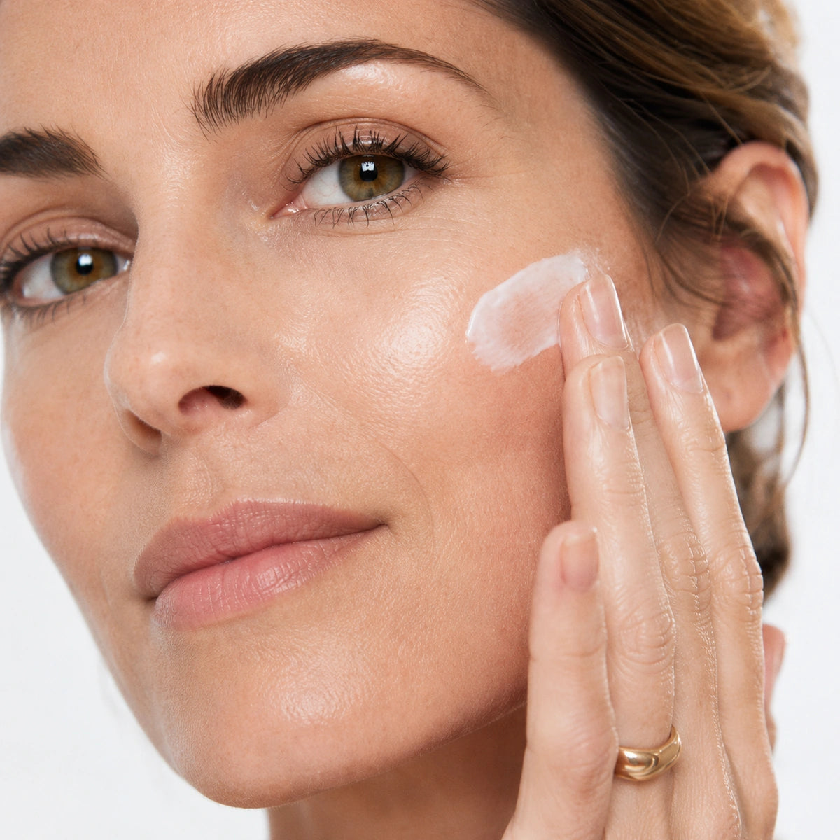 Femme appliquant L'Heure Souveraine crème de jour anti-âge de Valnay Paris sur la joue