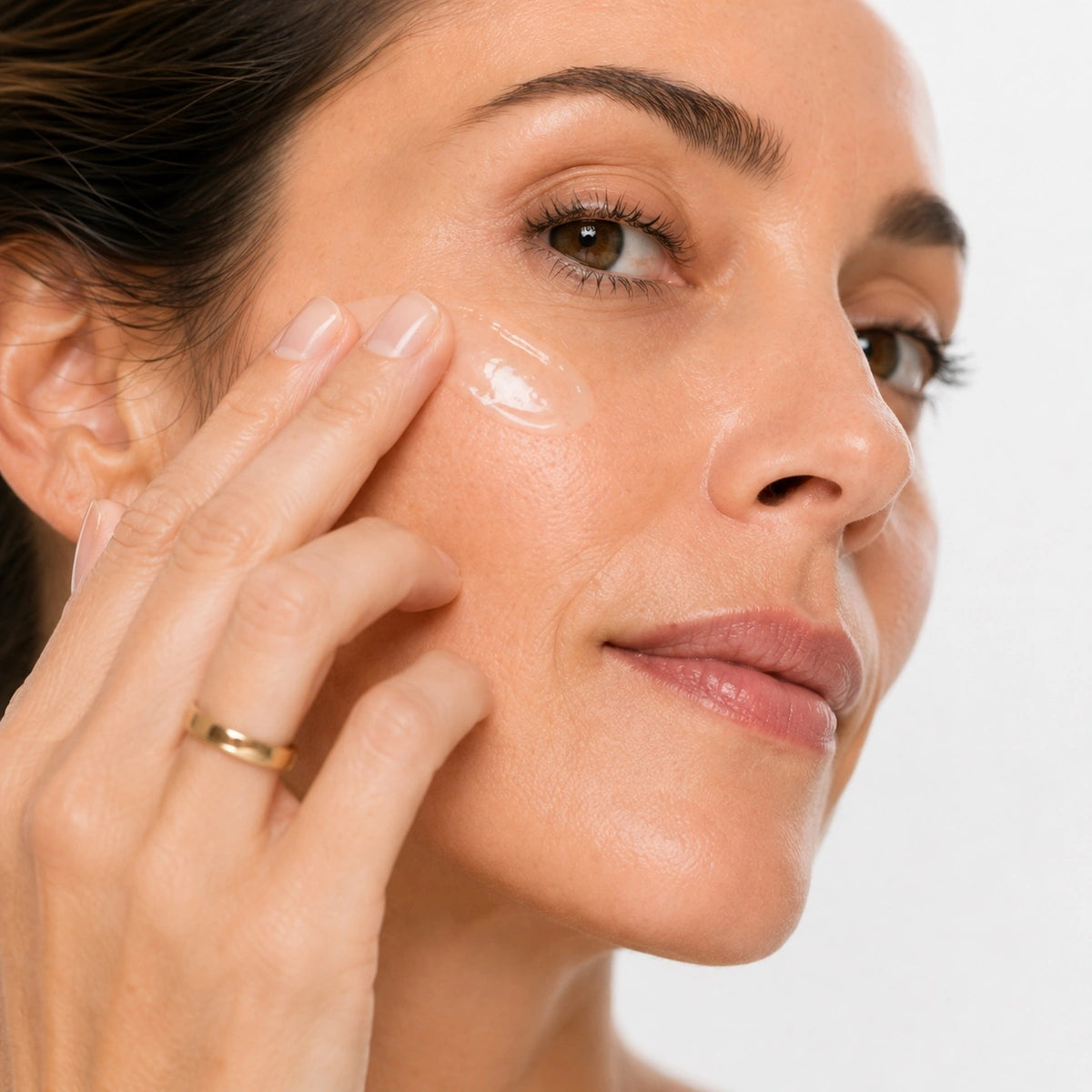 Femme appliquant délicatement le sérum anti-âge peptides L’Instinct Ambré sur la joue, révélant une texture légère et une peau lumineuse au fini éclatant.