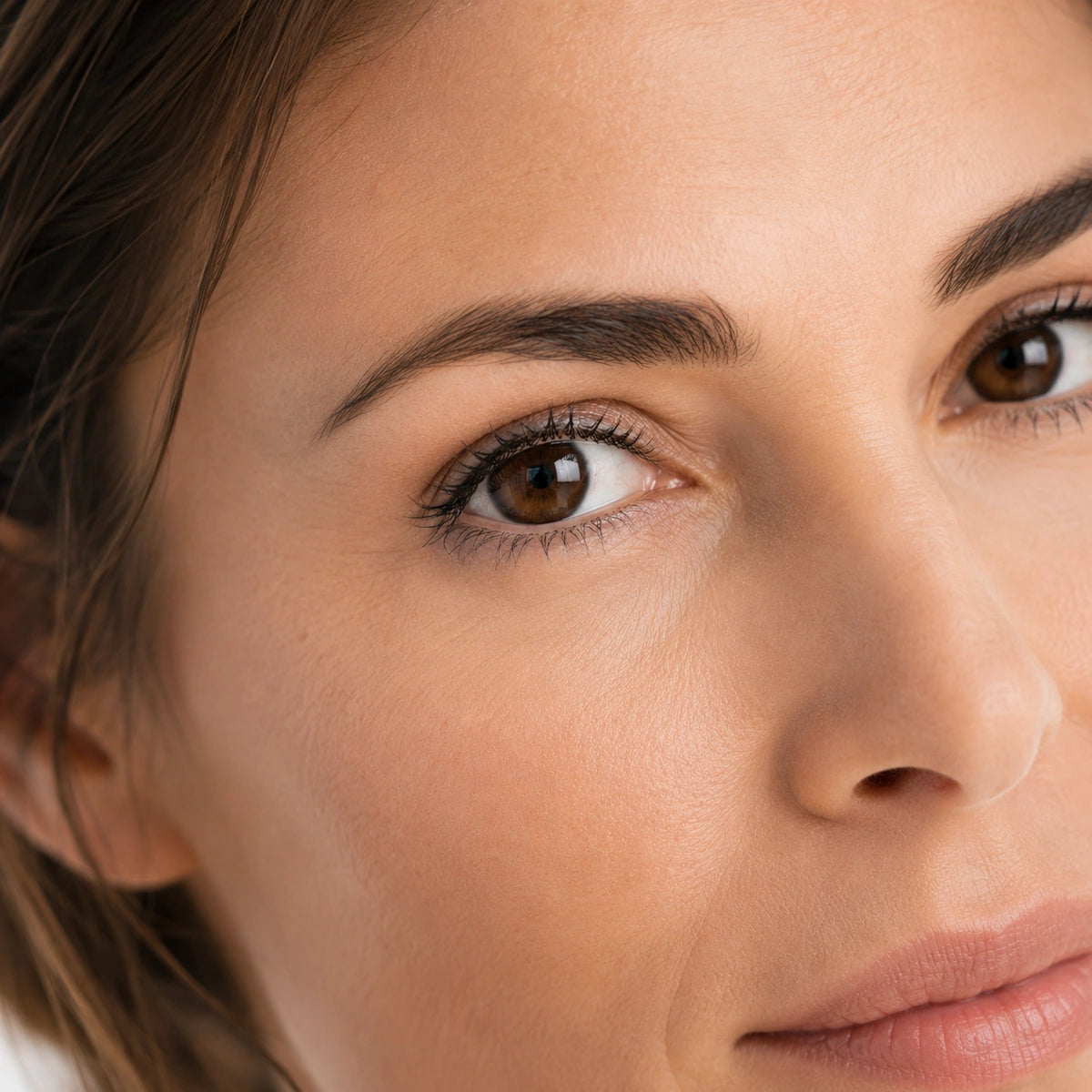 Gros plan du visage d'une femme au regard reposé et à la peau lumineuse illustrant les résultats de Le Premier Regard crème lissante contour des yeux de Valnay Paris
